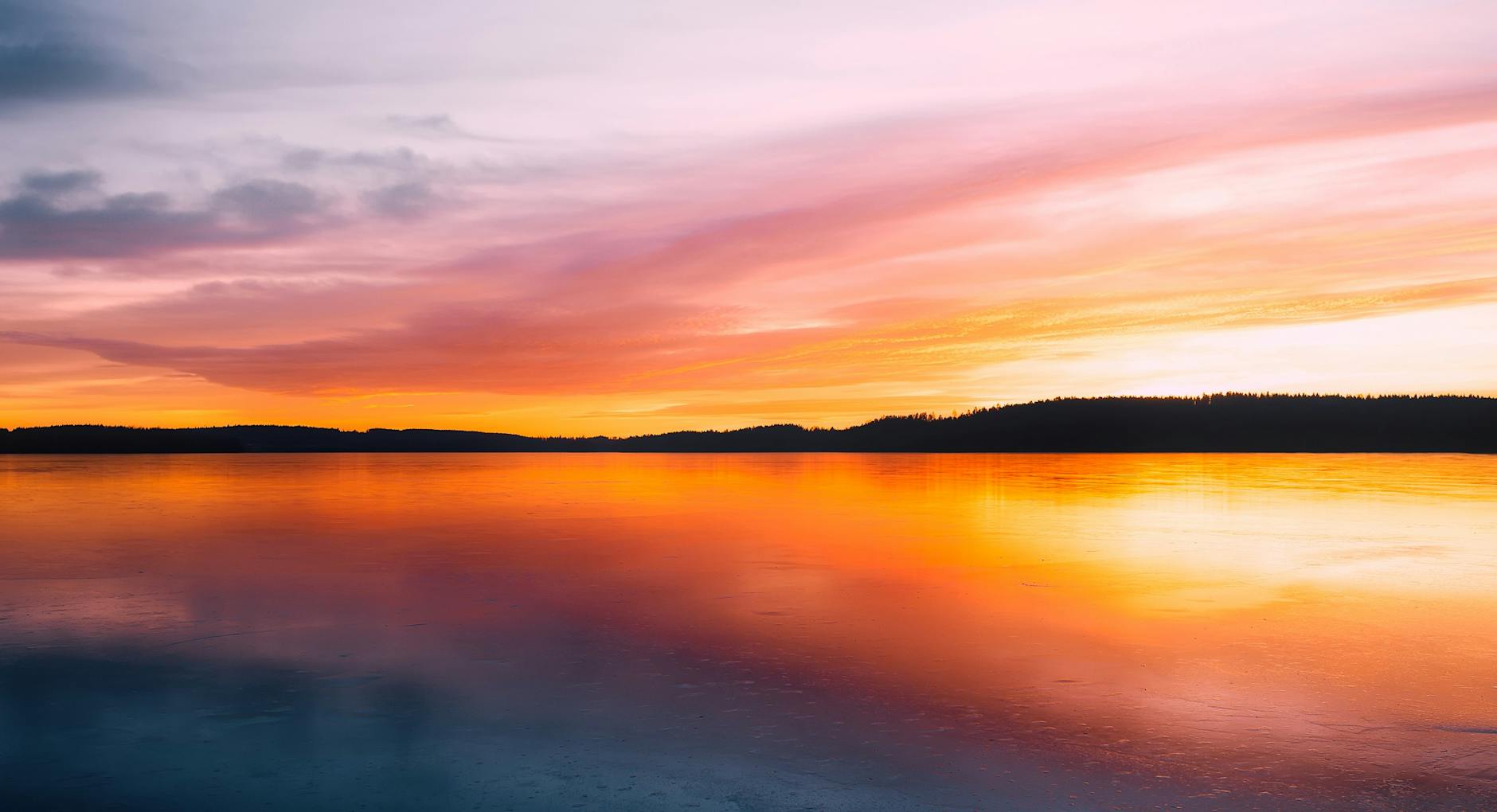 body of water beside mountain during golden hour